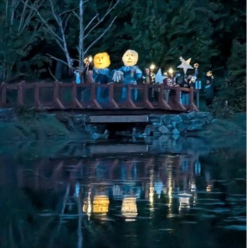 Over the footbridge — the luminaries reflected in the water.